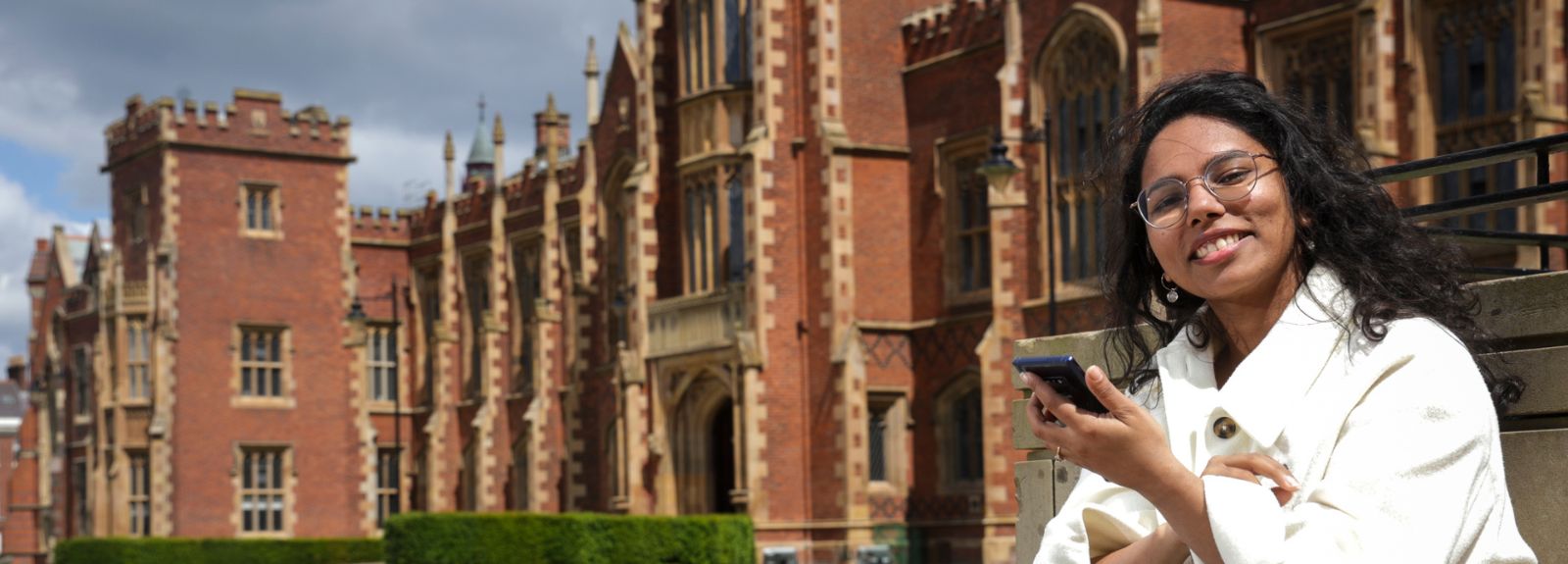 female student sitting outside Queen's main entrance